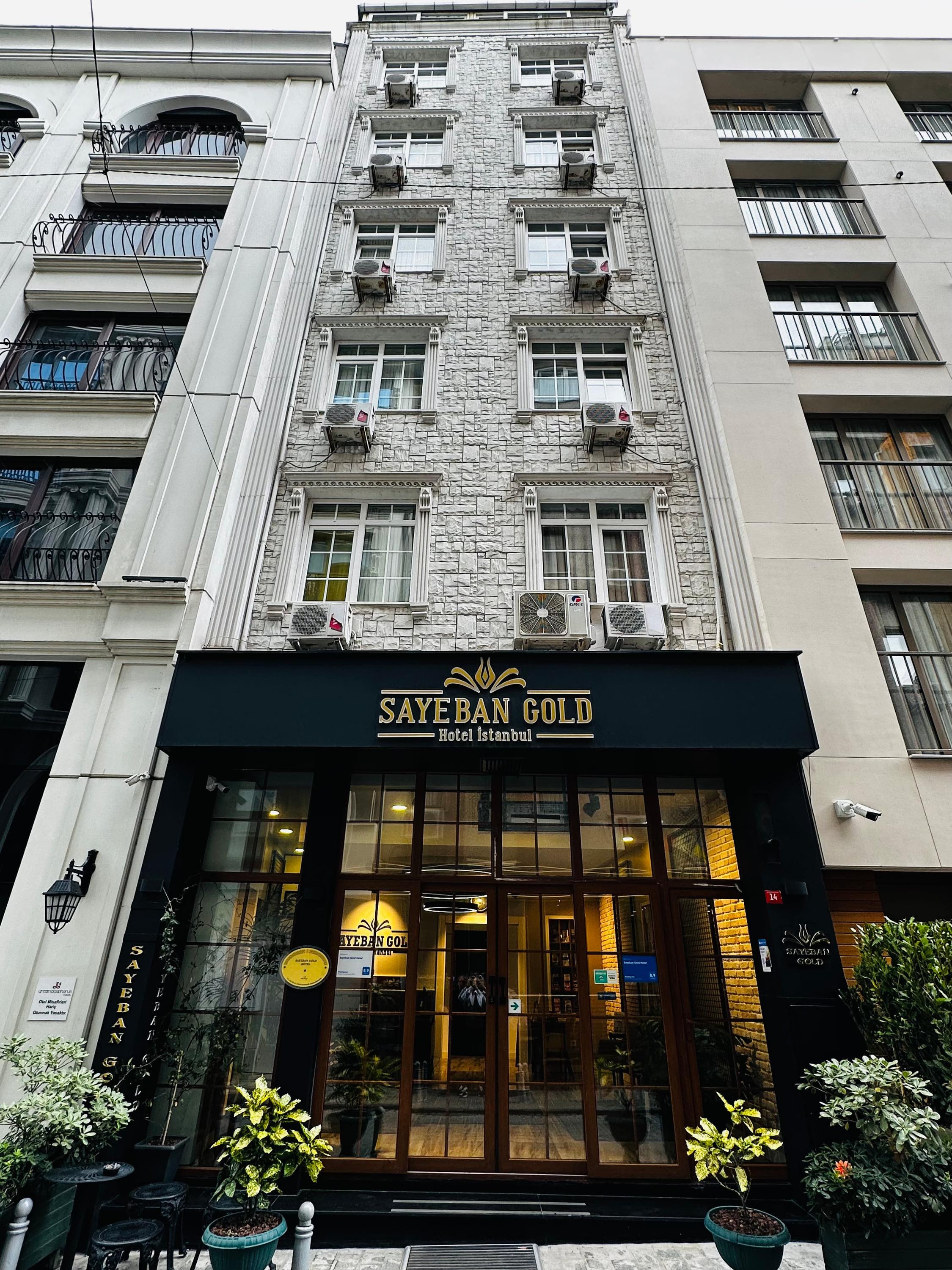 The hotel's stone façade and its glazed entrance beneath the gold sign