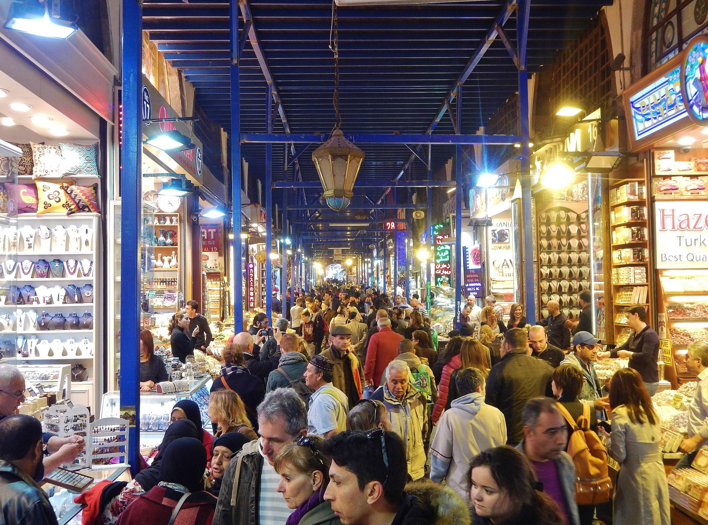 A crowded aisle of the Spice Bazaar under hanging lanterns