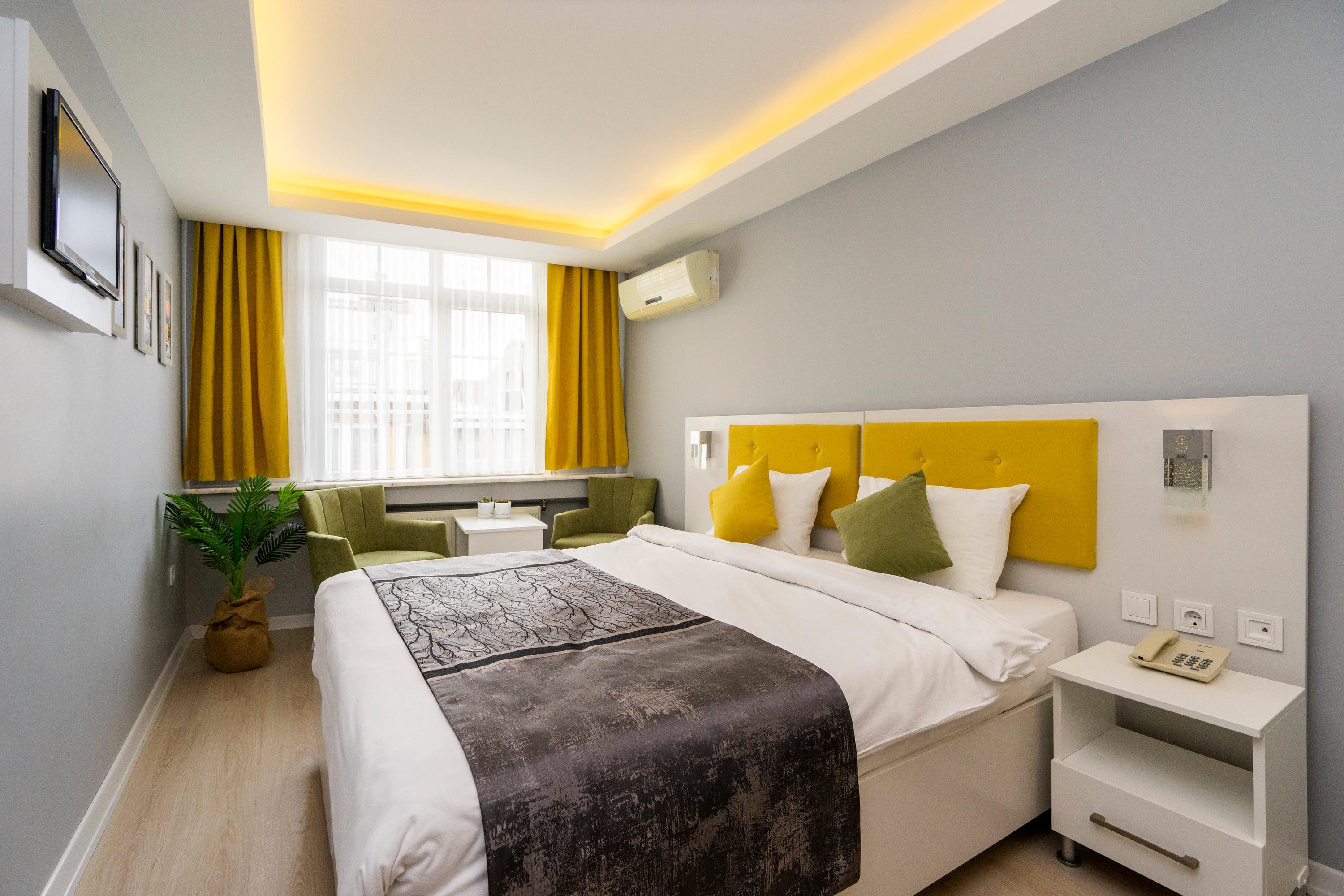 The grey-walled room with mustard curtains and olive armchairs