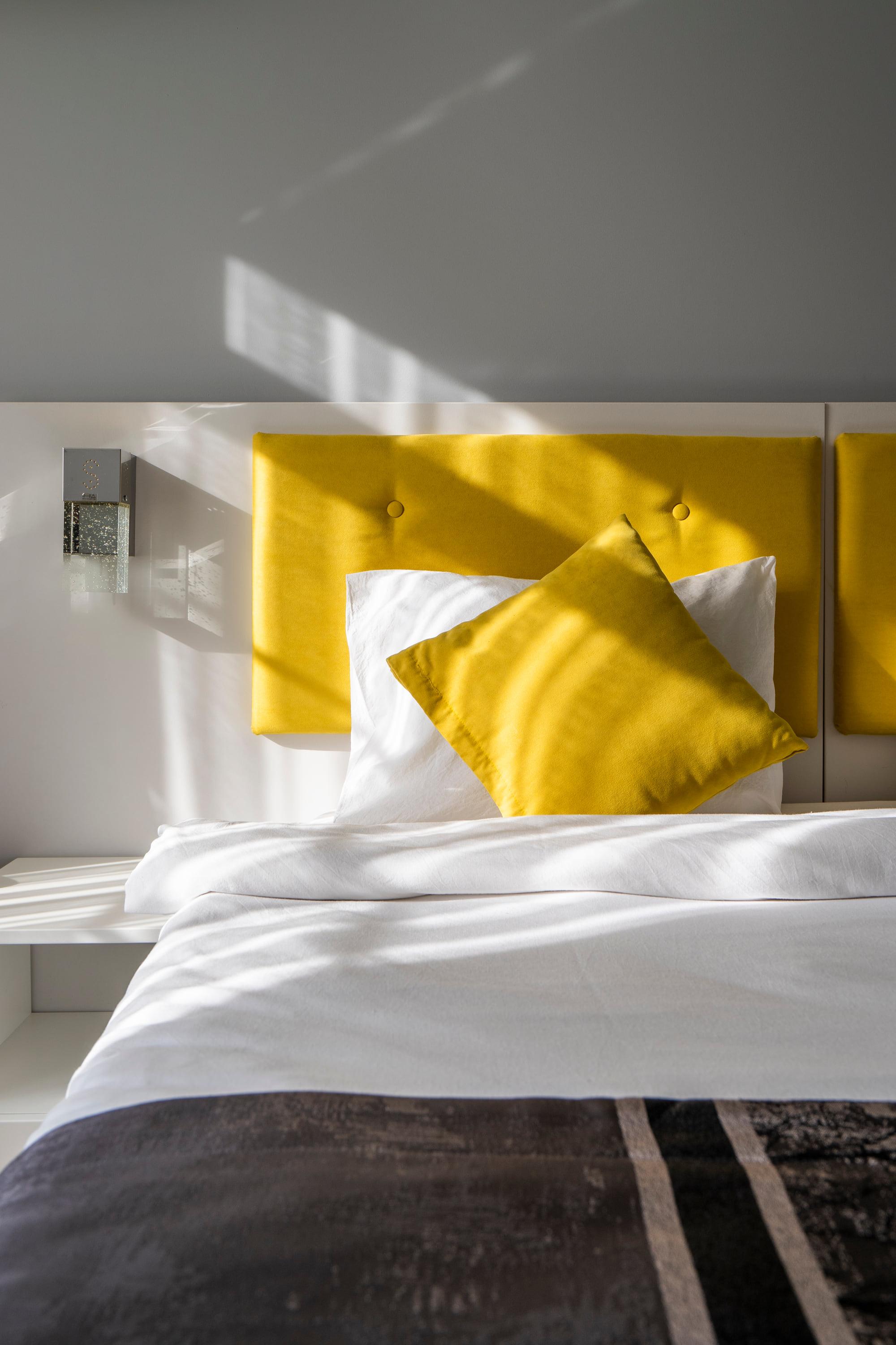 Daylight falling across the buttoned mustard headboard